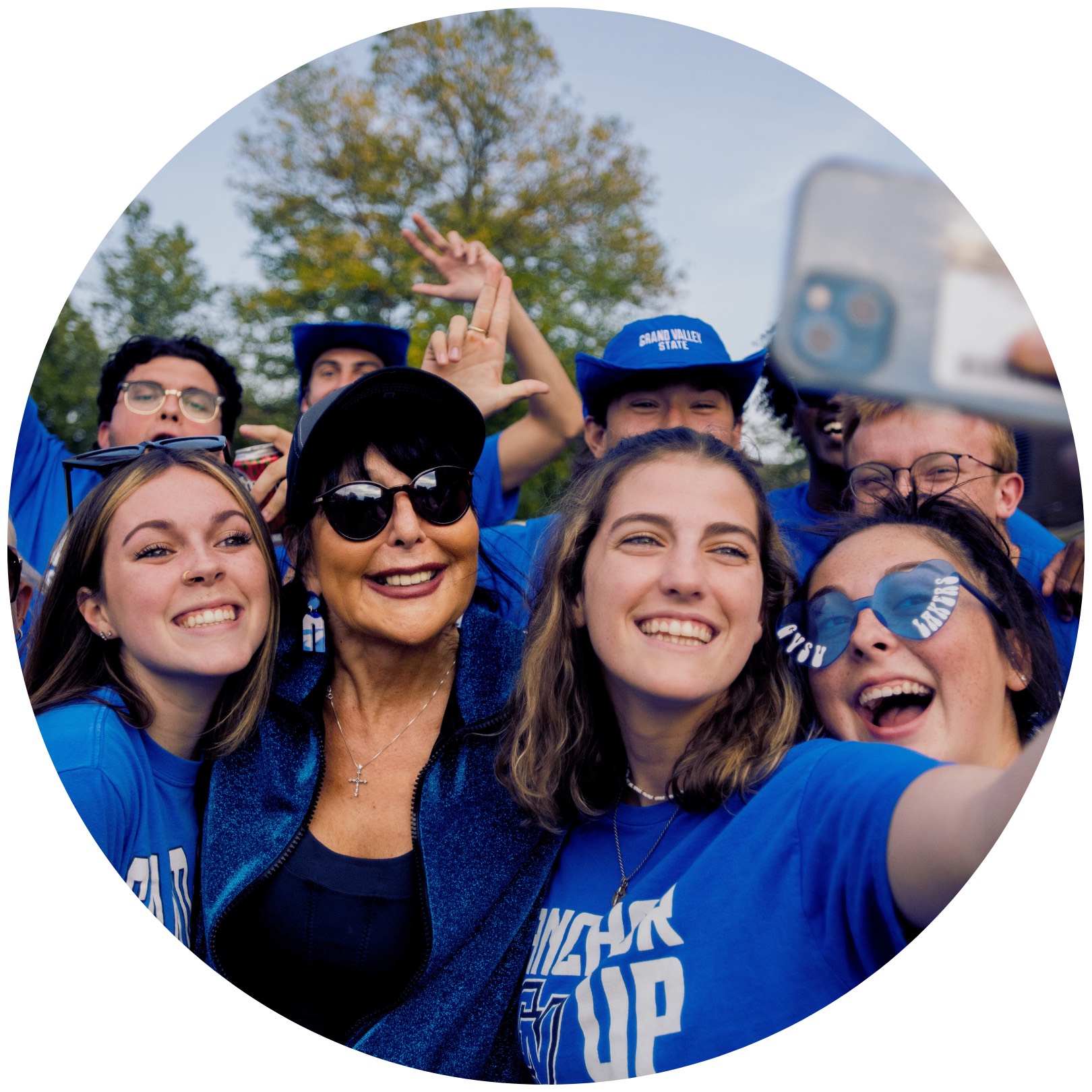 President Mantella taking a selfie with several students dressed up in blue laker gear.